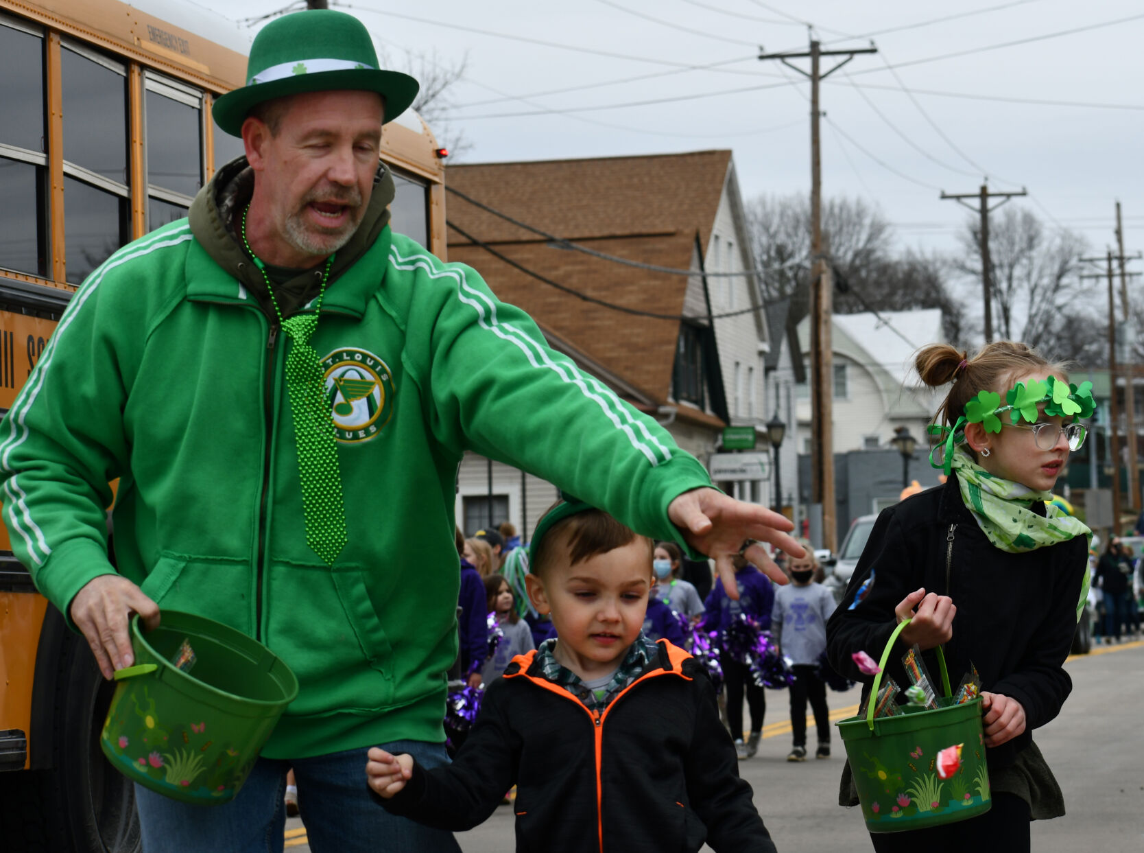 Three people walk the parade route handing out candy